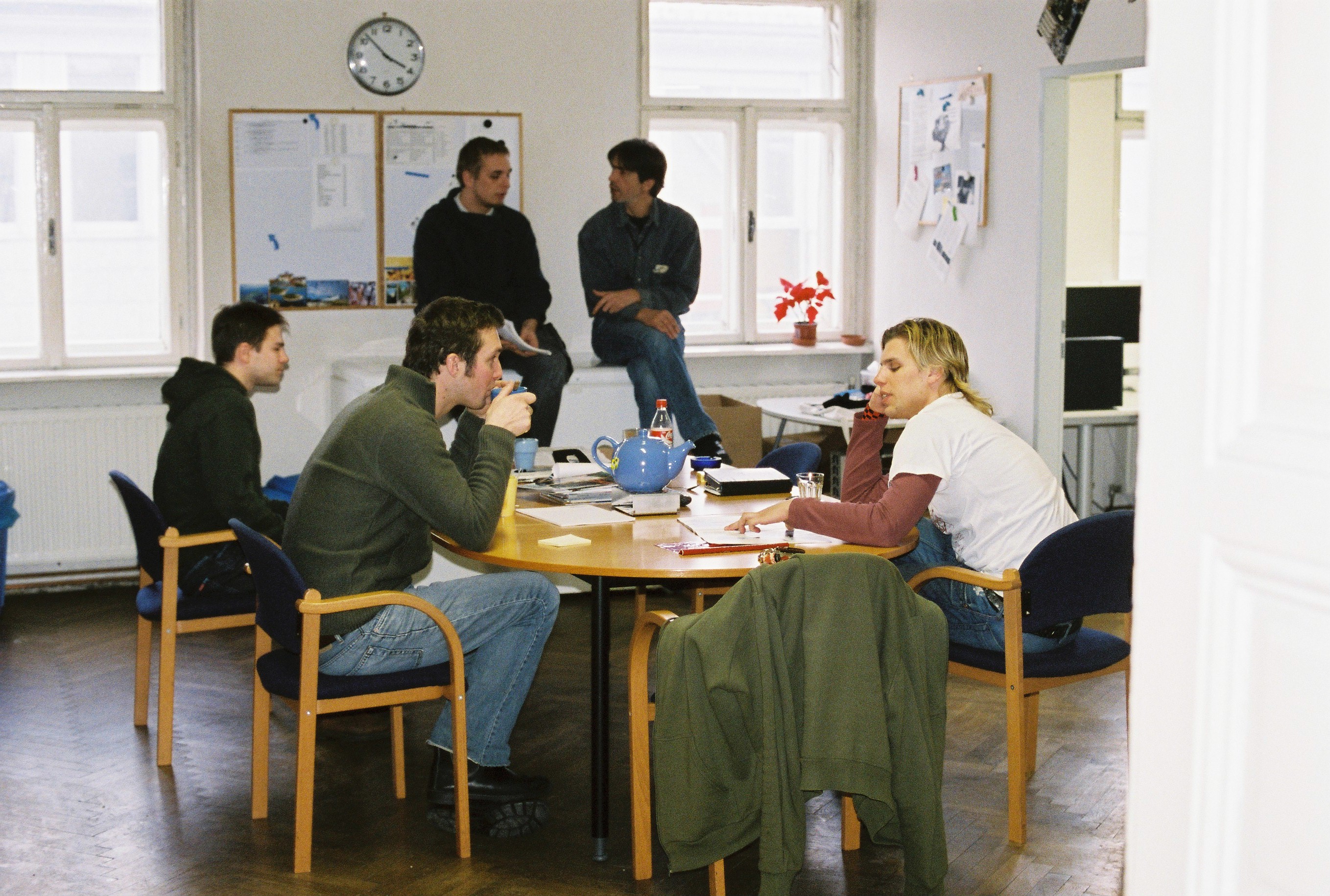 Diverse group meeting, office chairs, informal discussion, round table, teamwork, casual setting, bright room, brainstorm, professional collaboration, men and women interacting.