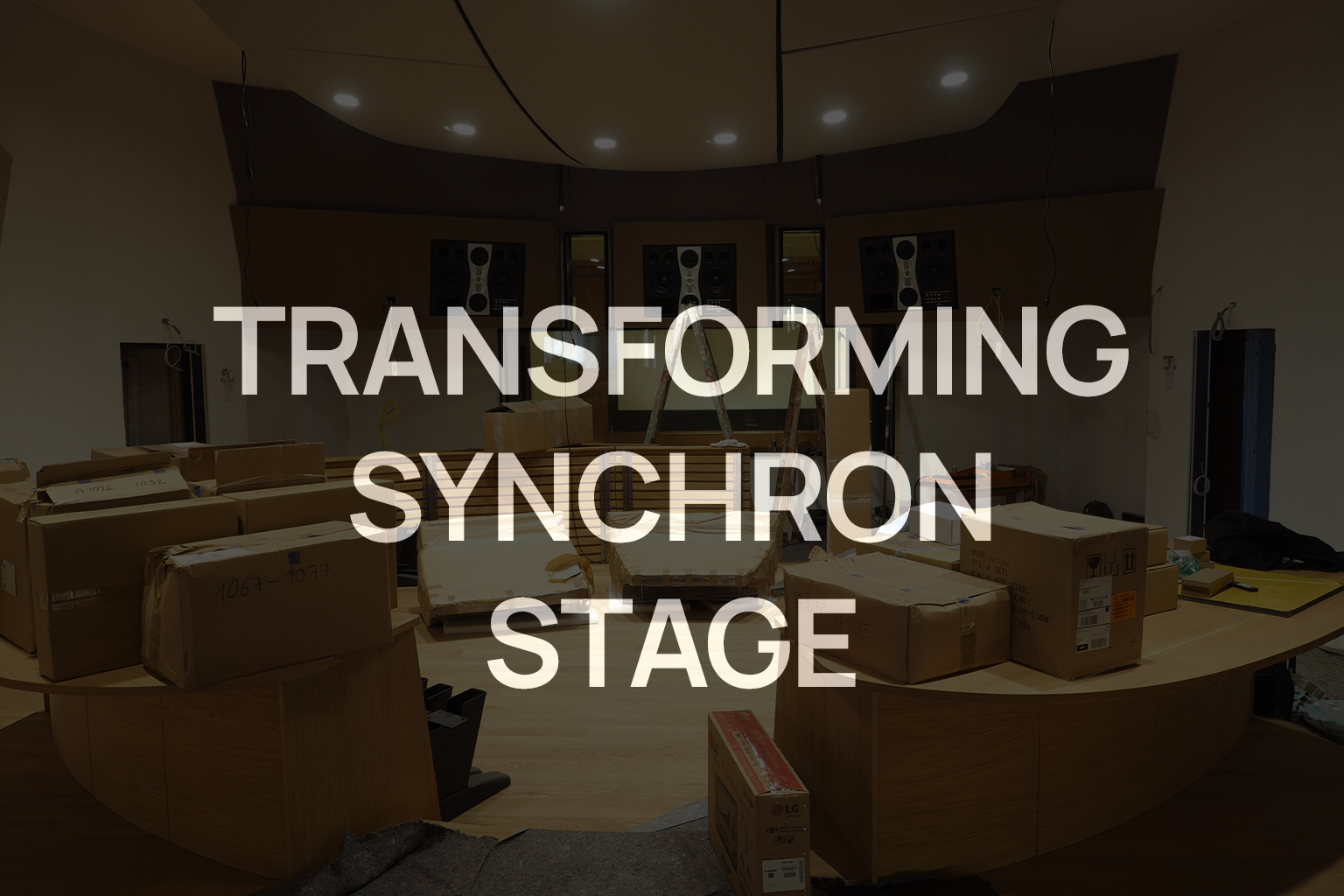 Control room filled with cardboard boxes and furniture, with bright text overlay TRANSFORMING SYNCHRON STAGE