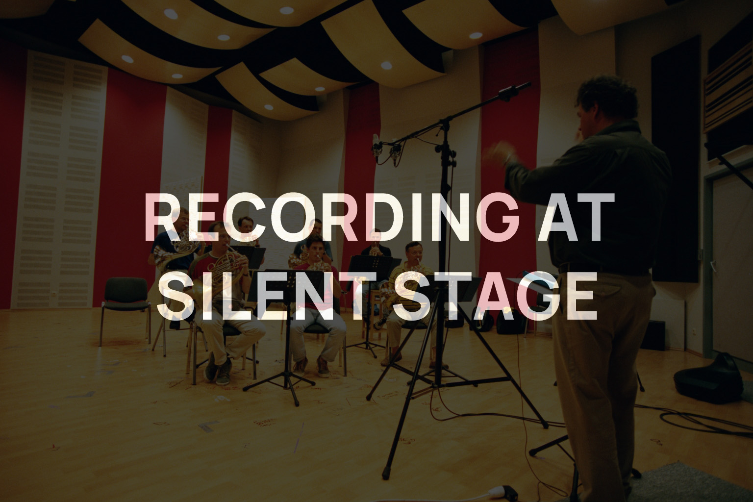 Musicians performing in a recording studio with a conductor, text overlay says Recording at Silent Stage.
