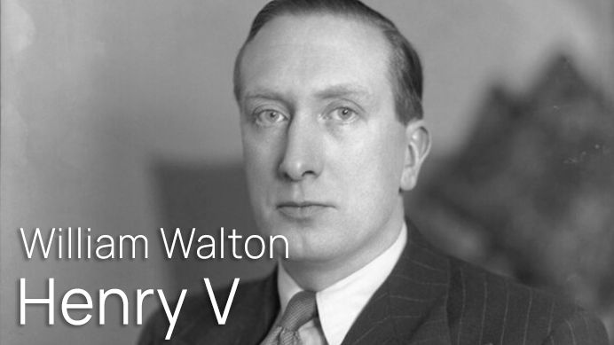 Black and white portrait of William Walton, composer for the 1944 film Henry V. He is looking directly at the viewer, wearing a suit and tie.