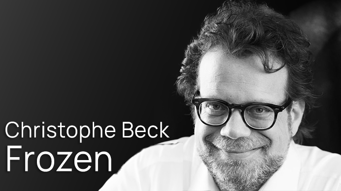 Black and white portrait of Christophe Beck, director of the movie Frozen, smiling and wearing glasses.