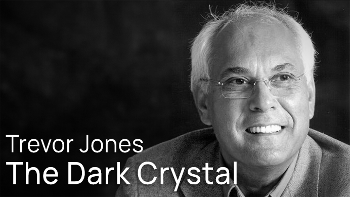Black and white portrait of Trevor Jones, the director of The Dark Crystal, smiling and wearing glasses.