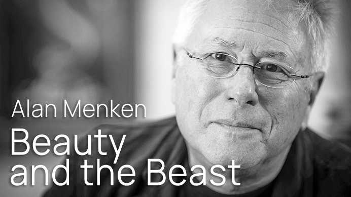 Black and white photo of Alan Menken, composer for Beauty and the Beast, wearing glasses and looking directly at the viewer.