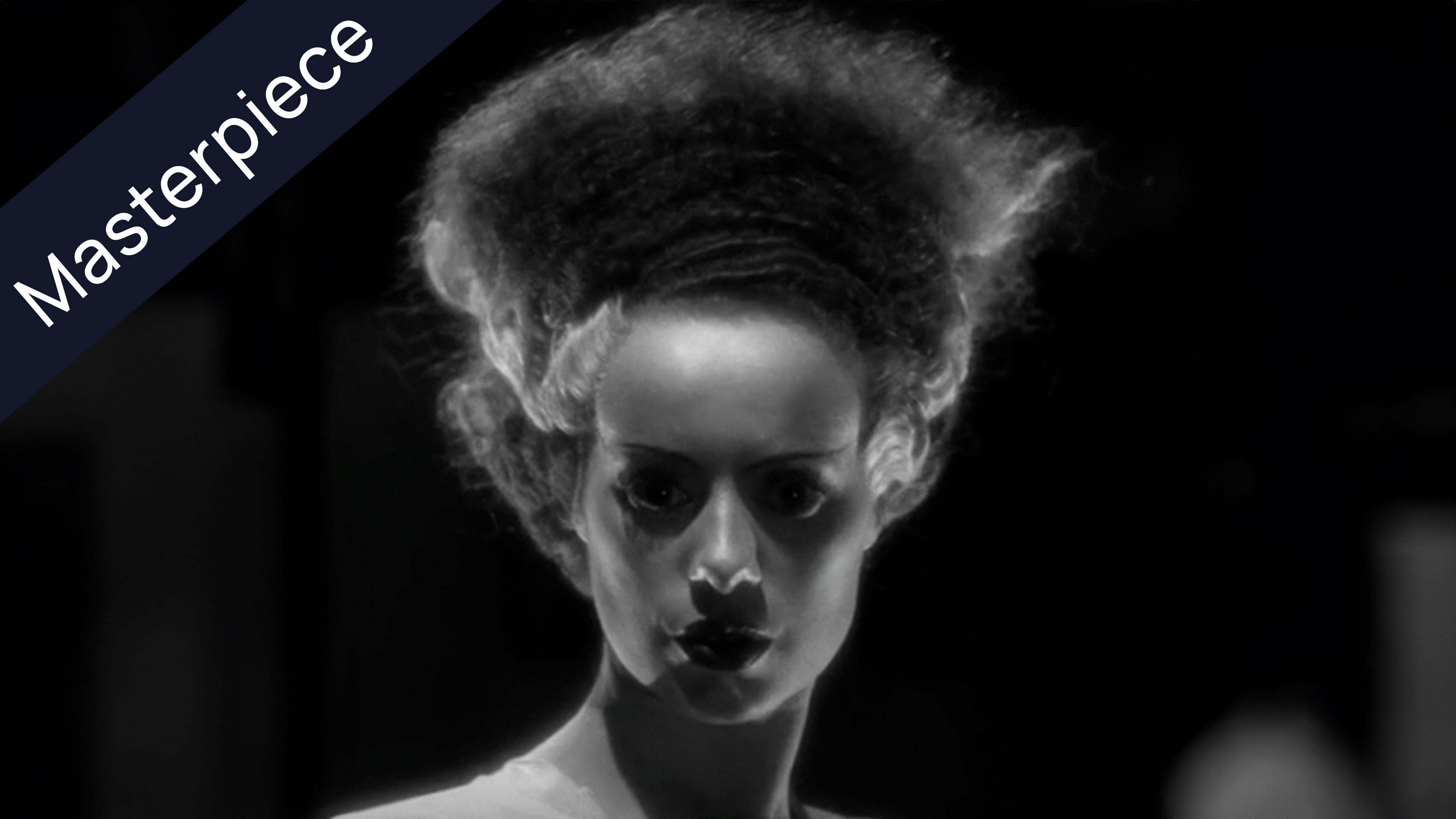 Black and white image of the Bride of Frankenstein looking directly forward, with large, frizzy hair and dark eyes and lips, on a black background. Ribbon with the word Masterpiece crosses the top left corner.