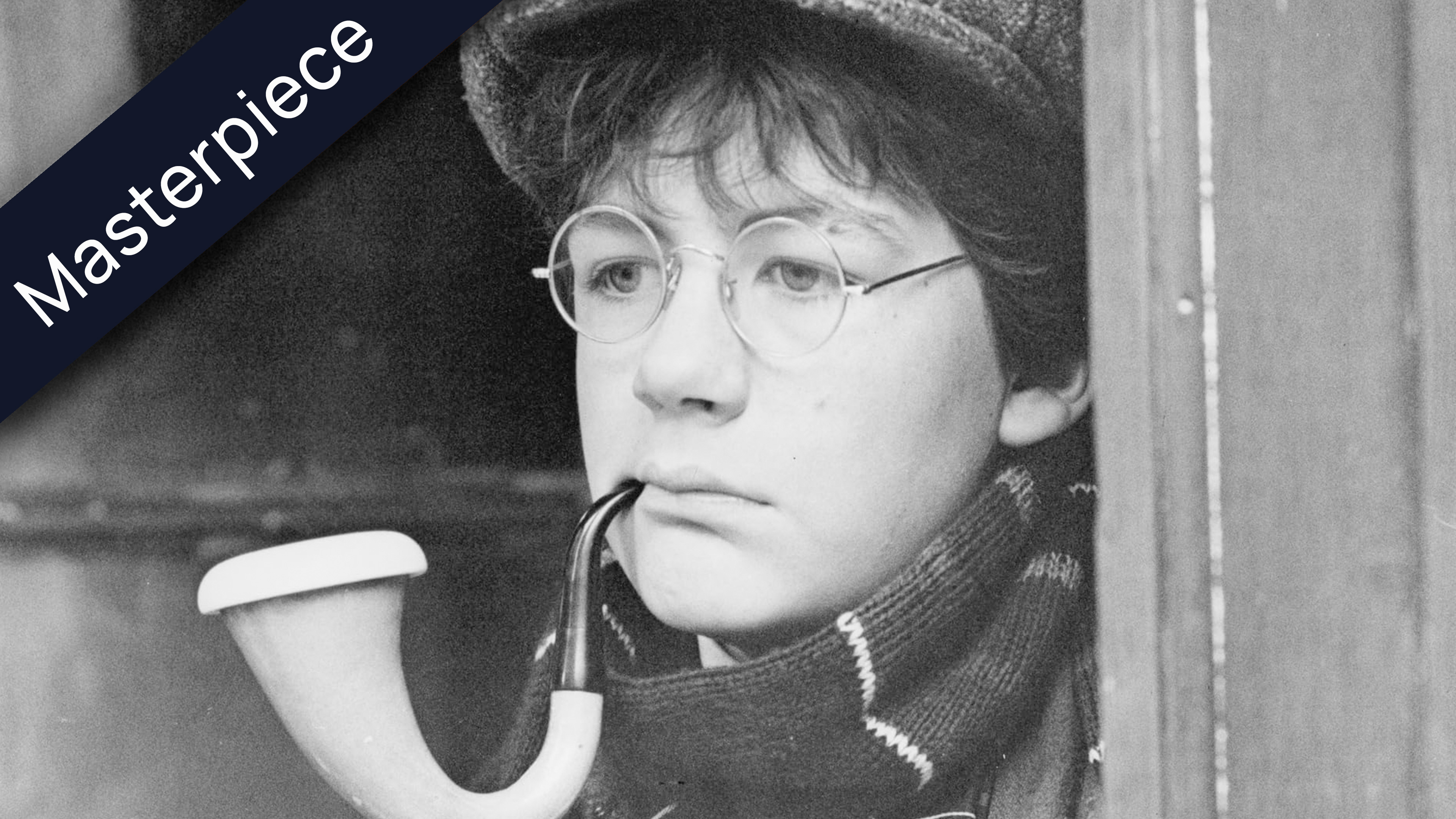 Black and white photo of a serious young boy in a flat cap and glasses, with a pipe in his mouth, wearing a patterned scarf. The word Masterpiece is angled in the top left corner.