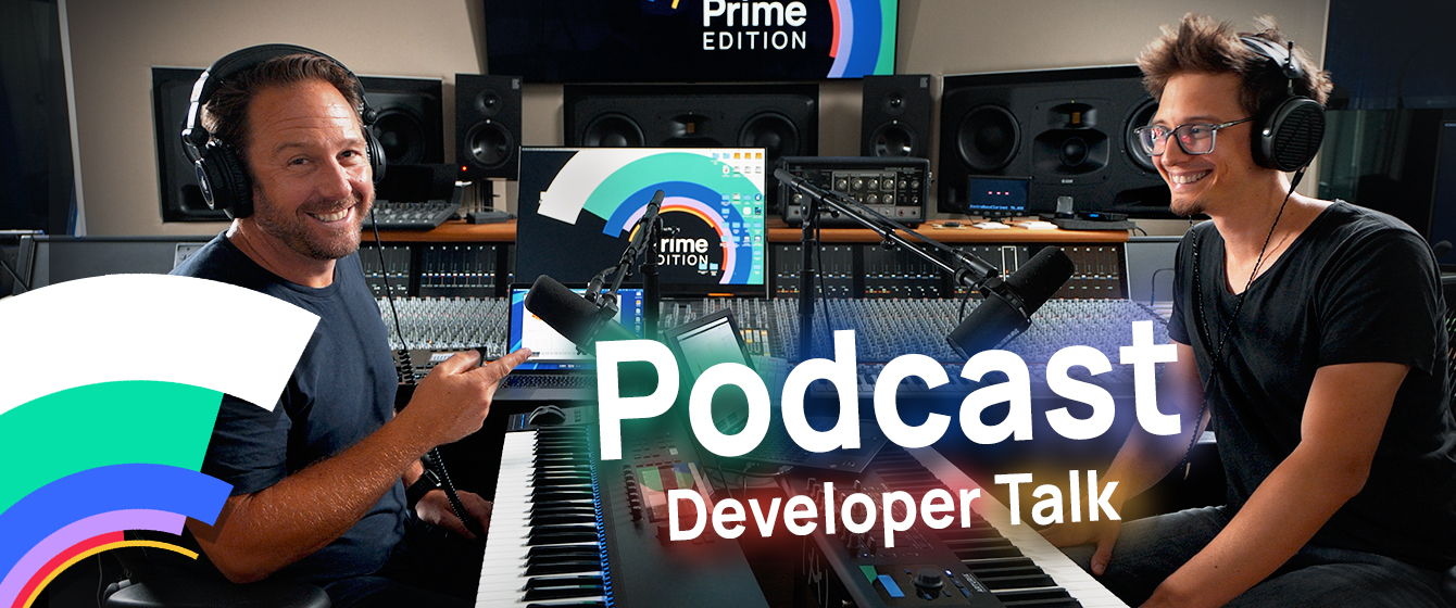 Two men in headphones smiling, sitting in a music studio with keyboards and microphones, with text overlay Podcast Developer Talk.