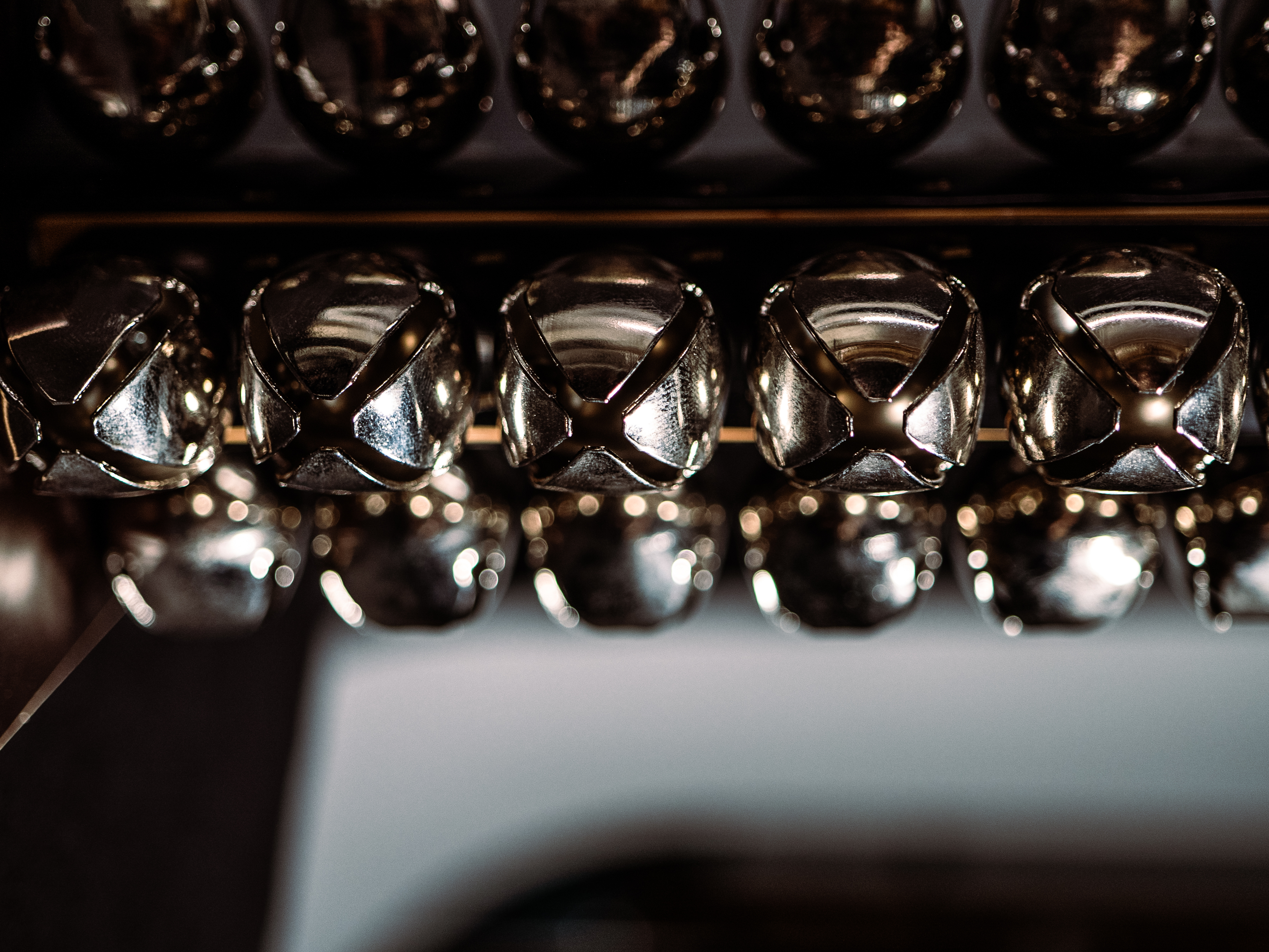 Array of shiny silver sleigh bells on a shelf, with bokeh lights reflecting off their metallic surface, creating a festive holiday atmosphere.