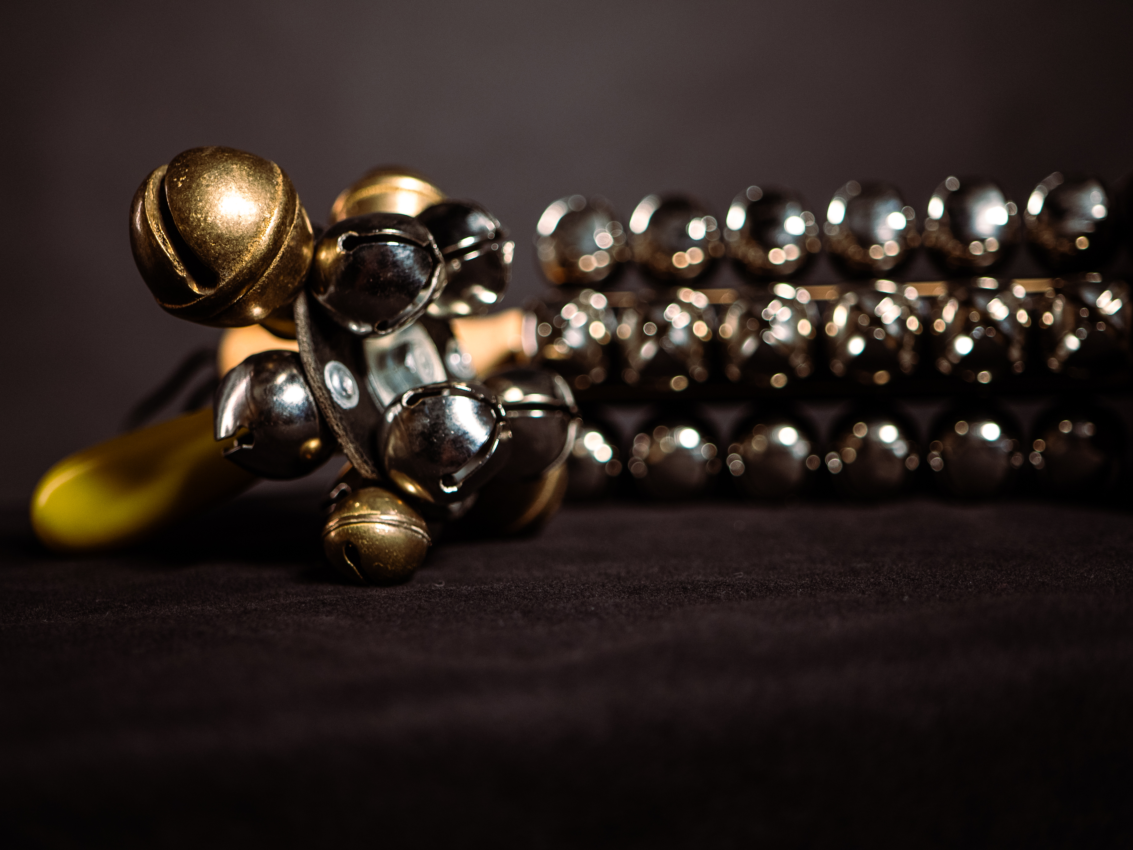 Jingle bells and sleigh bells, musical instruments for percussion and Christmas songs, against a dark backdrop.