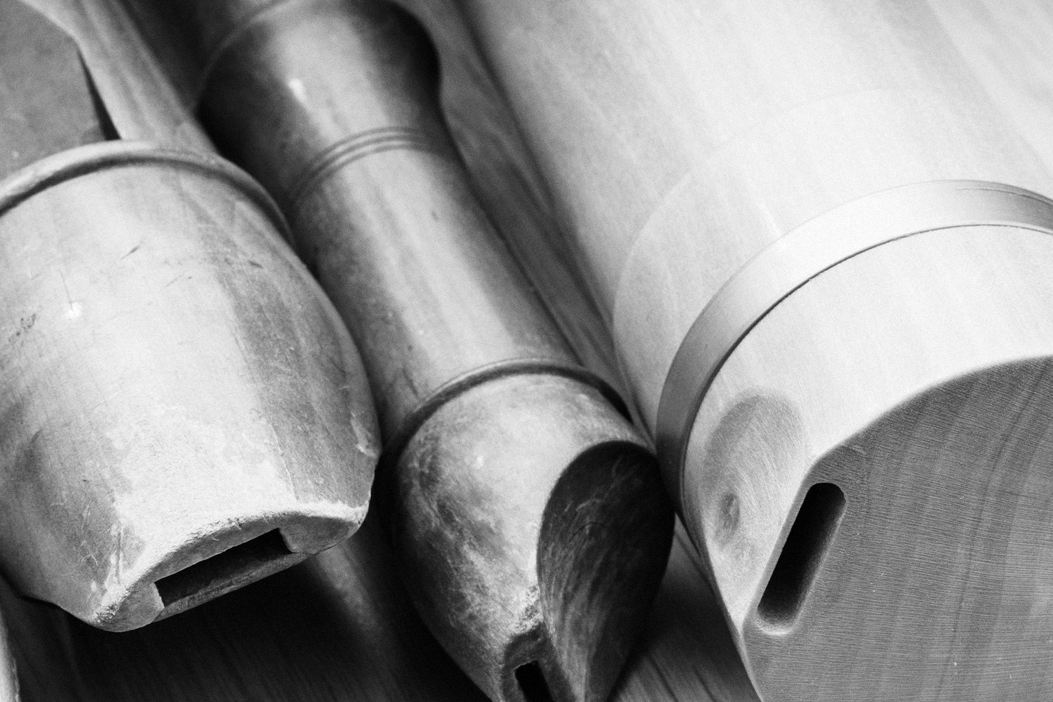 Black and white close-up of three wooden recorders, showing their bodies, windways, and feet.