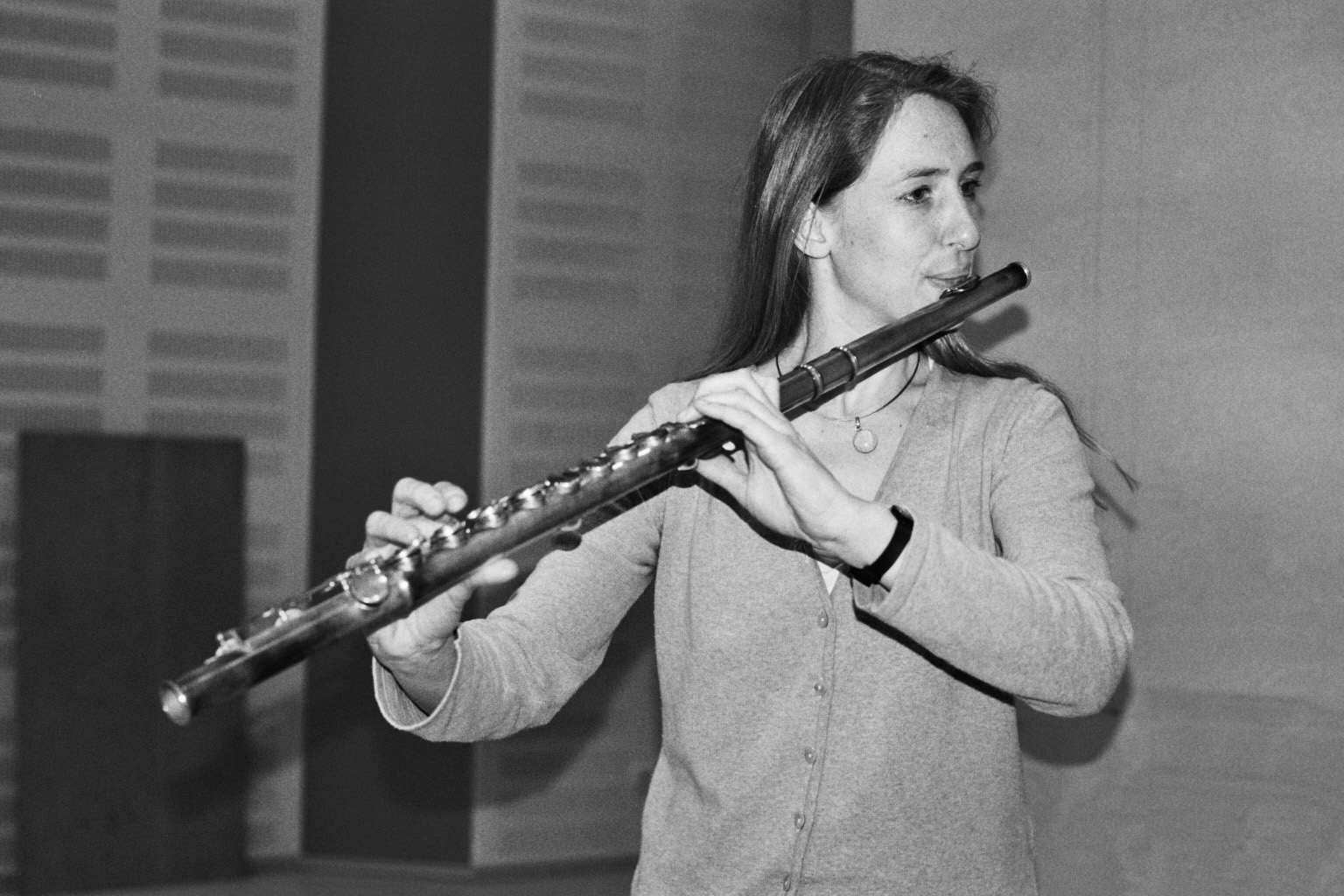 Black and white full shot of a woman with long hair playing the flute.