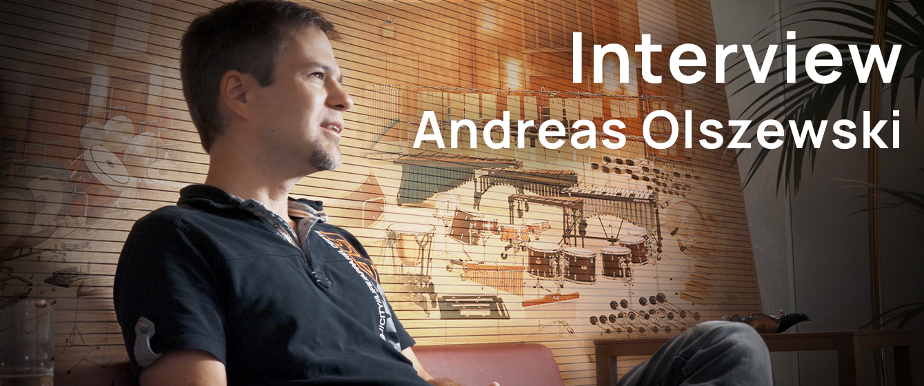 Portrait of Andreas Olszewski during an interview, with text Interview Andreas Olszewski on an overlay.