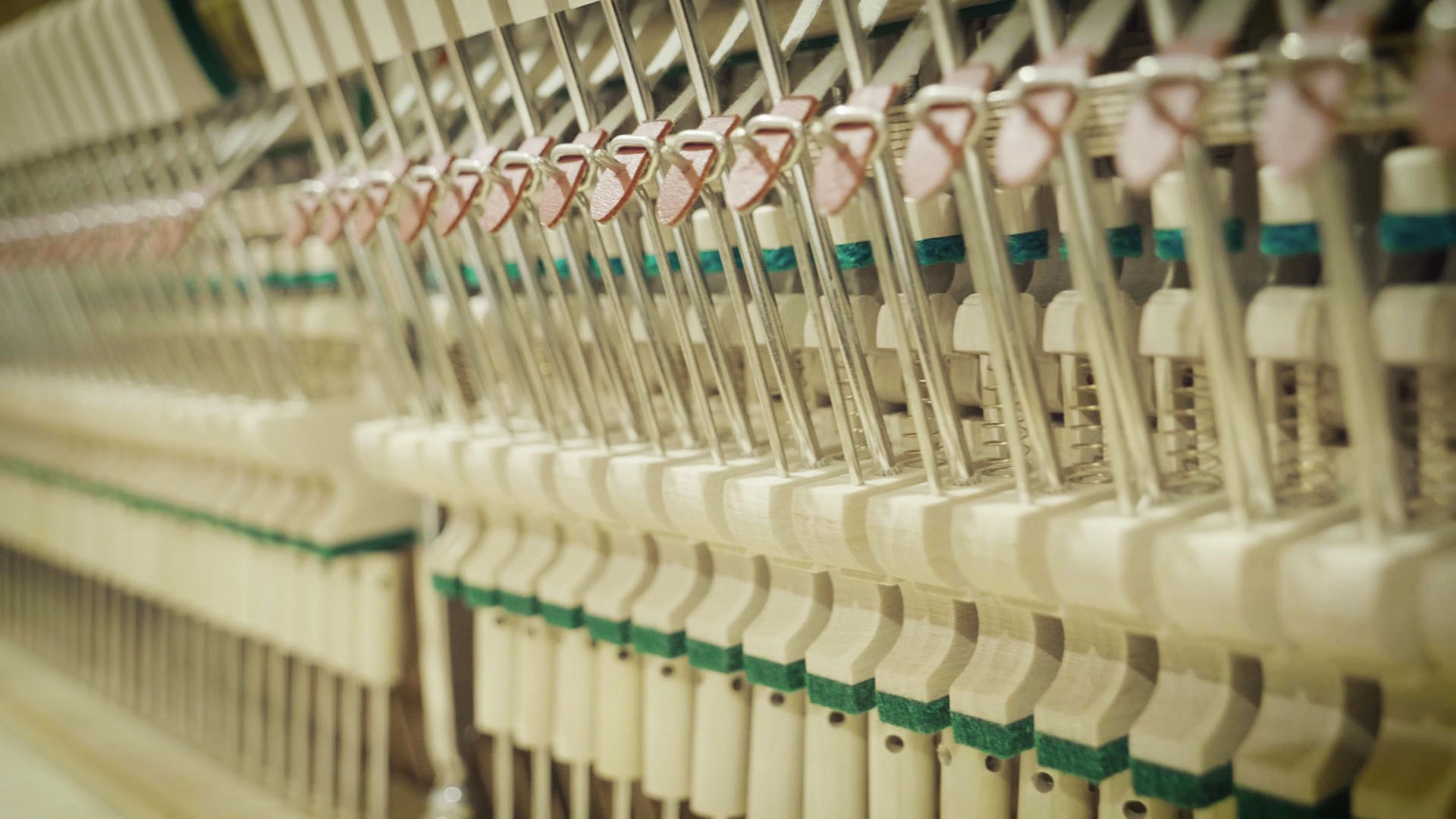 Inside view of upright piano action showing rows of hammers, dampers, and white key mechanisms