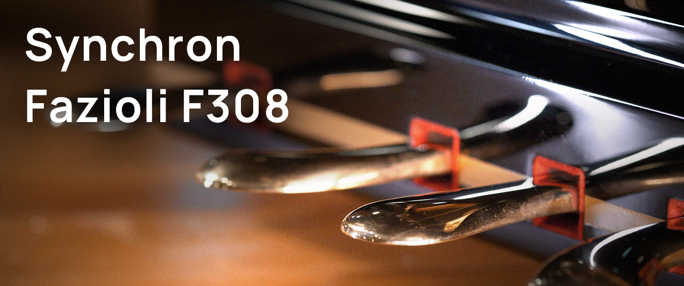 Close up of a Fazioli F308 grand piano's three polished brass pedals, with Synchron Fazioli F308 text overlaid in white.